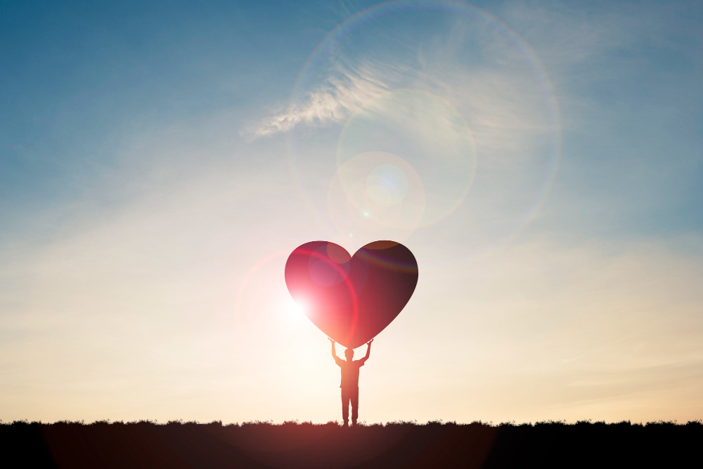 silhouette-man-show-two-hand-rise-up-carrying-heart-with-sunlight-blue-sky-valentine-s-day-concept